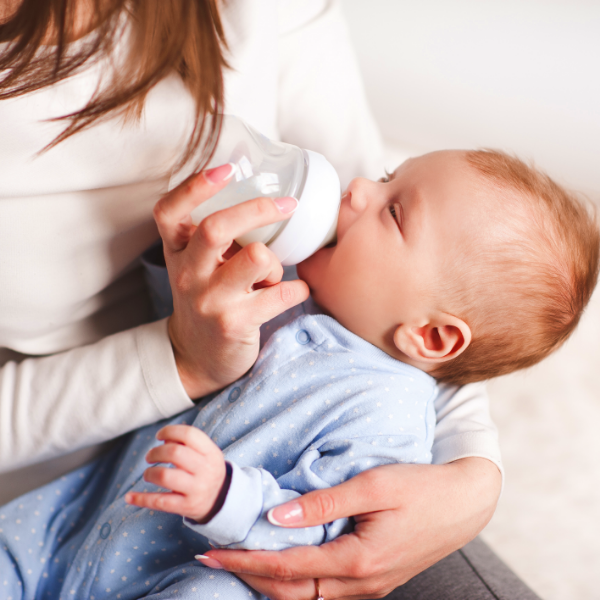a woman feeding her baby through a baby bottle