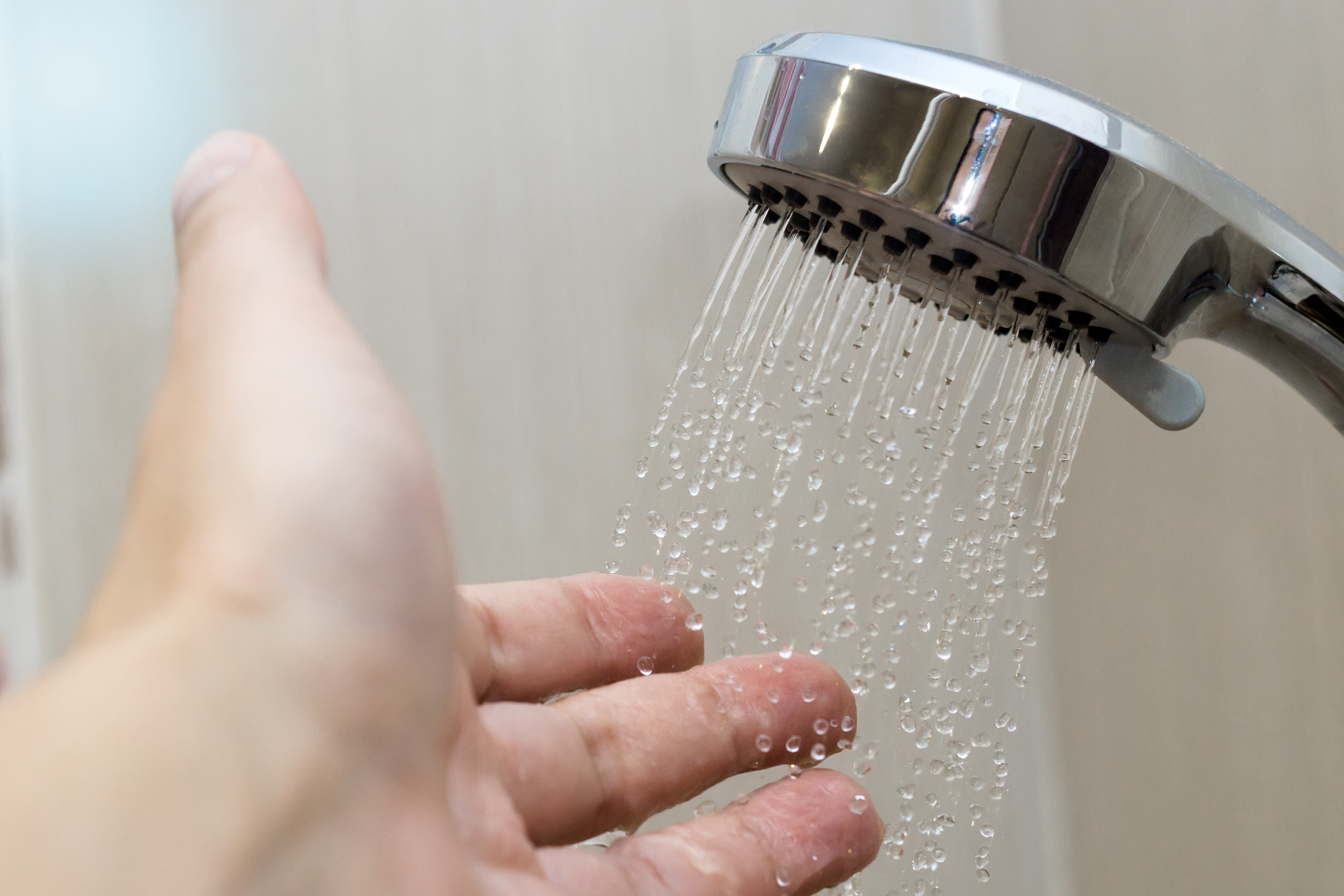 Closeup of showerhead spraying water on hand