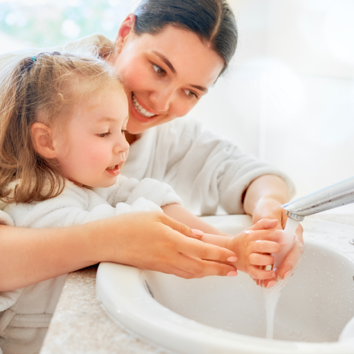 a woman teaching a little girl how to wash her hands 