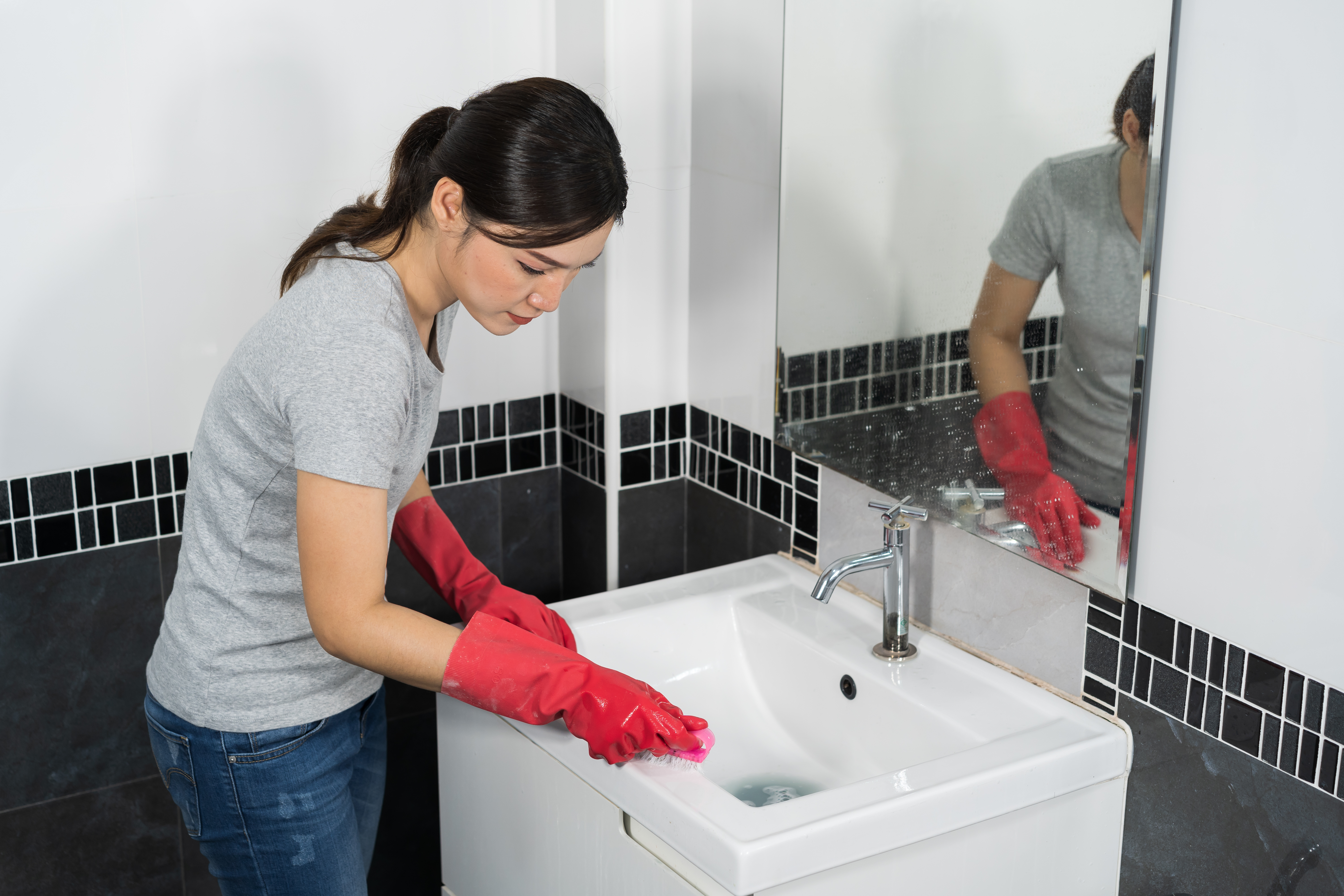 Female wearing red gloves cleaning sink