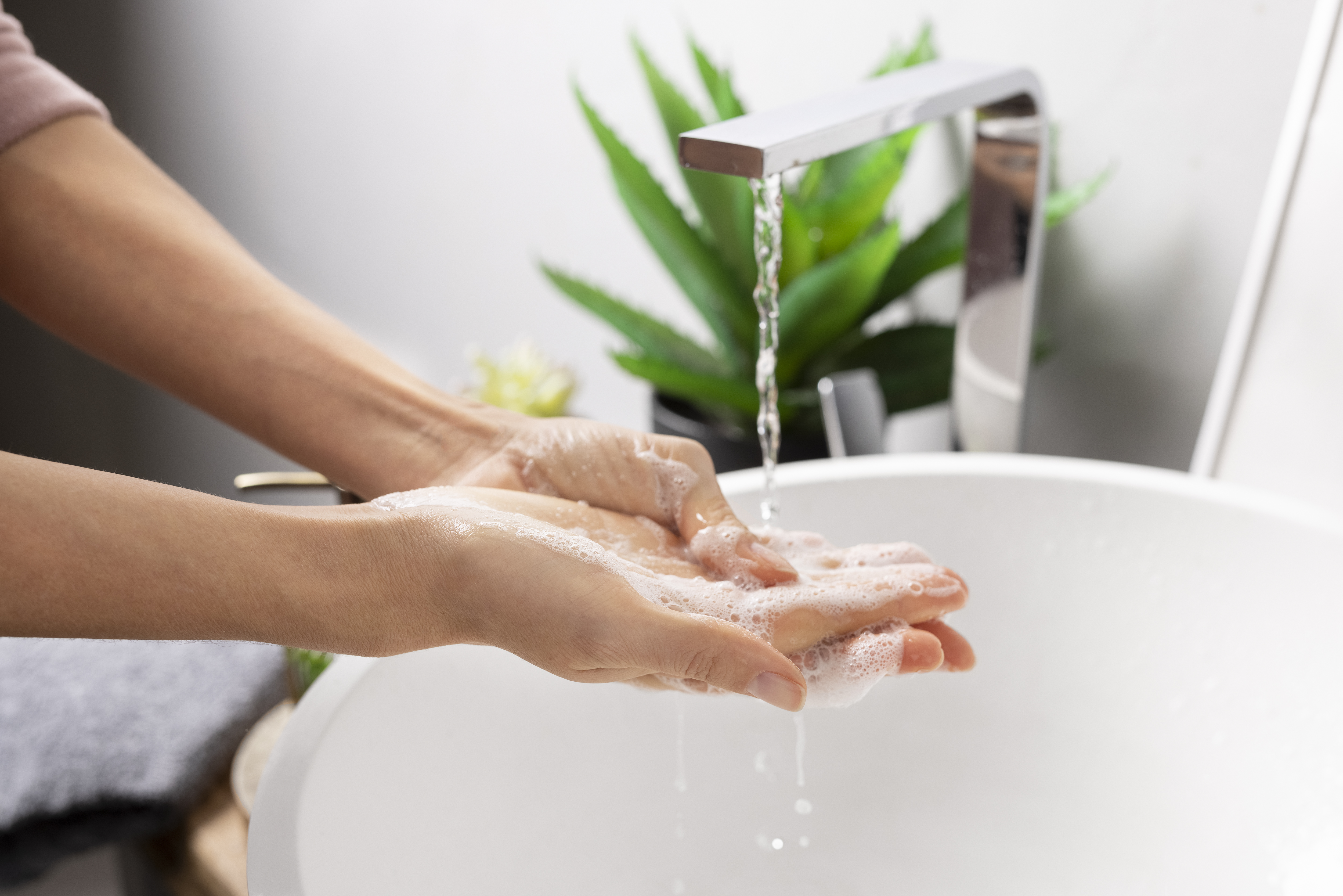 A person's hands being washed under running water with dettol soap.