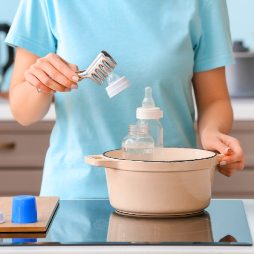 Mother sterilizing baby bottles by boiling in a pot on stove